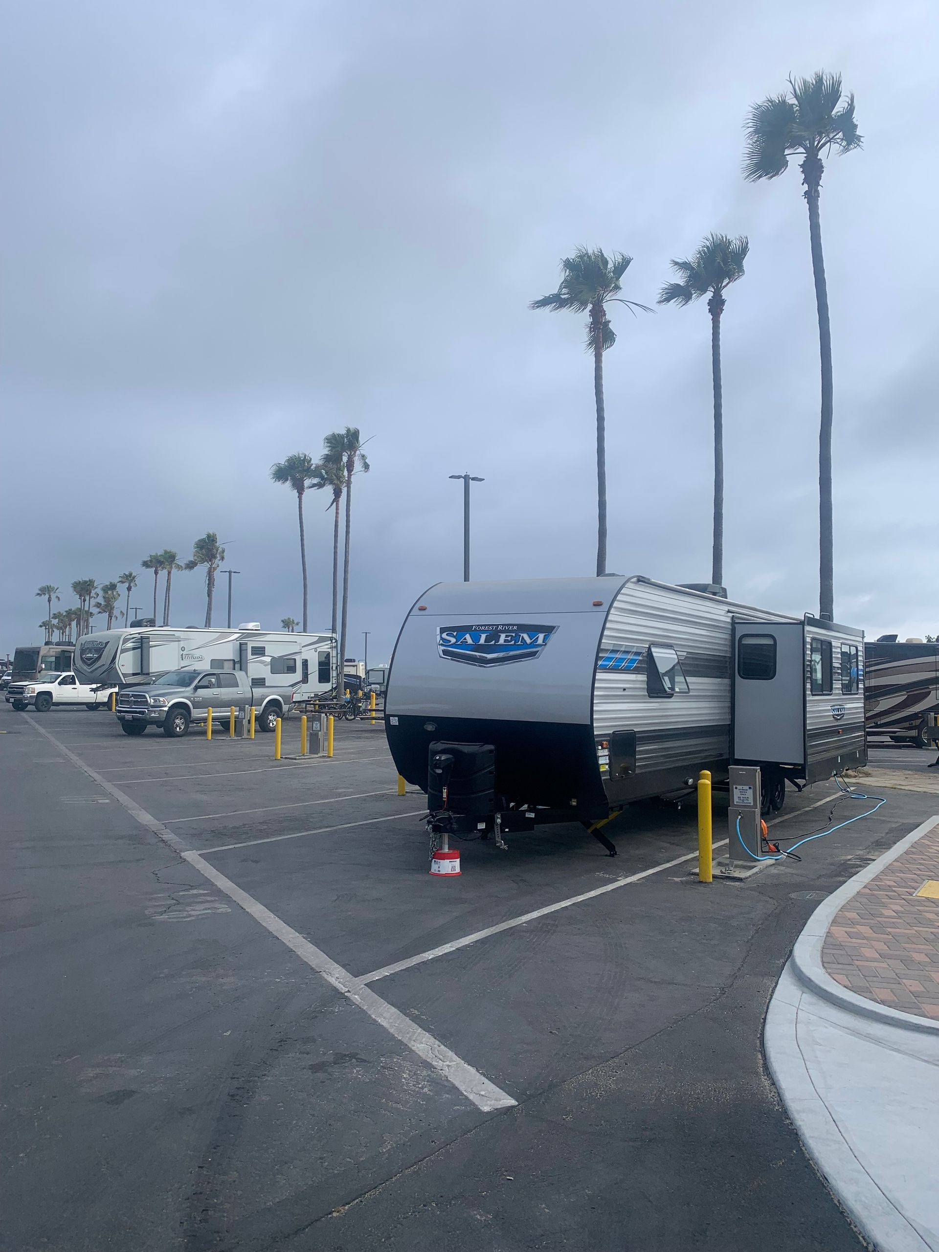 a rv is parked in a parking lot with palm trees in the background .