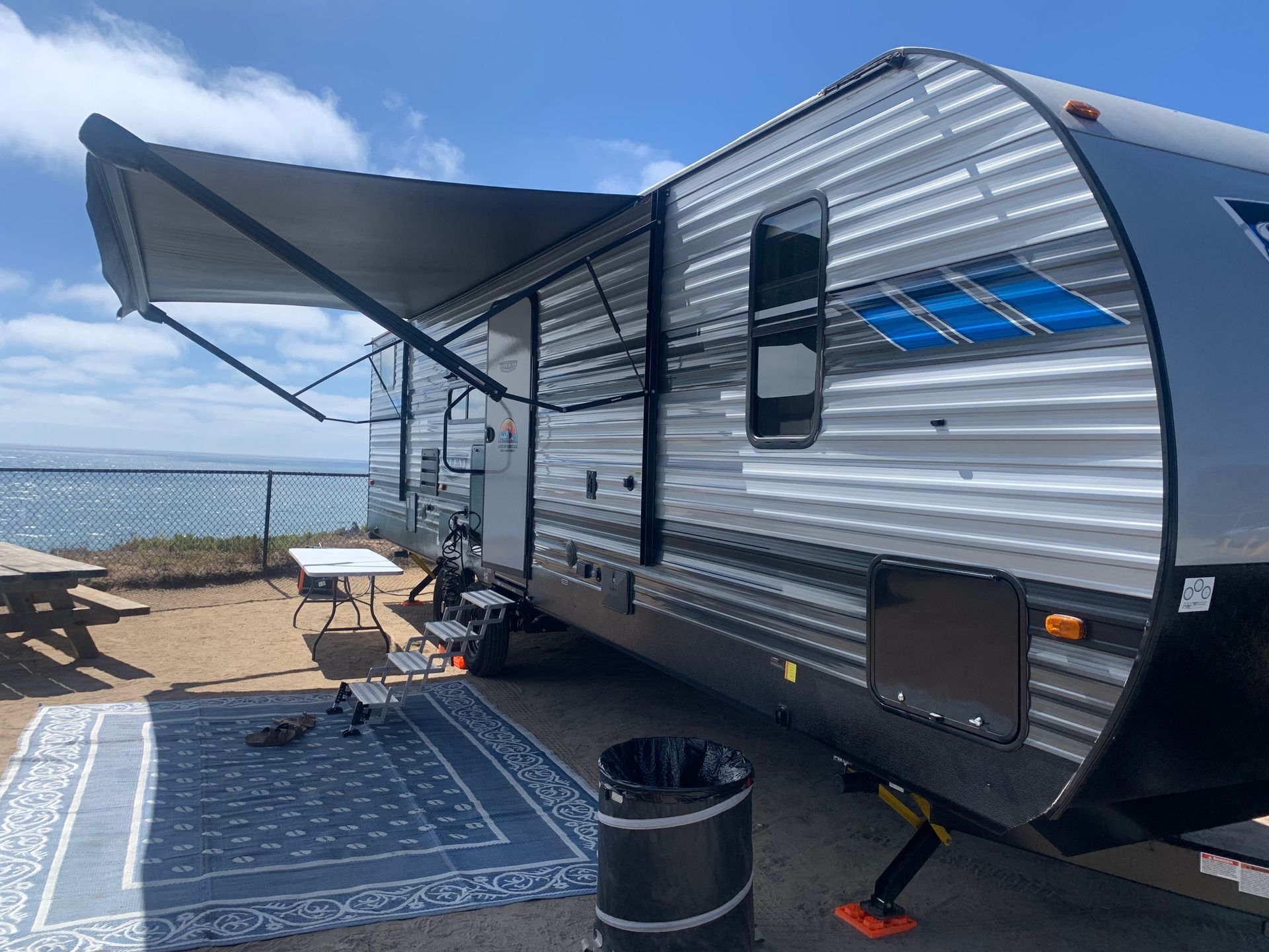 a rv is parked in a parking lot next to the ocean .