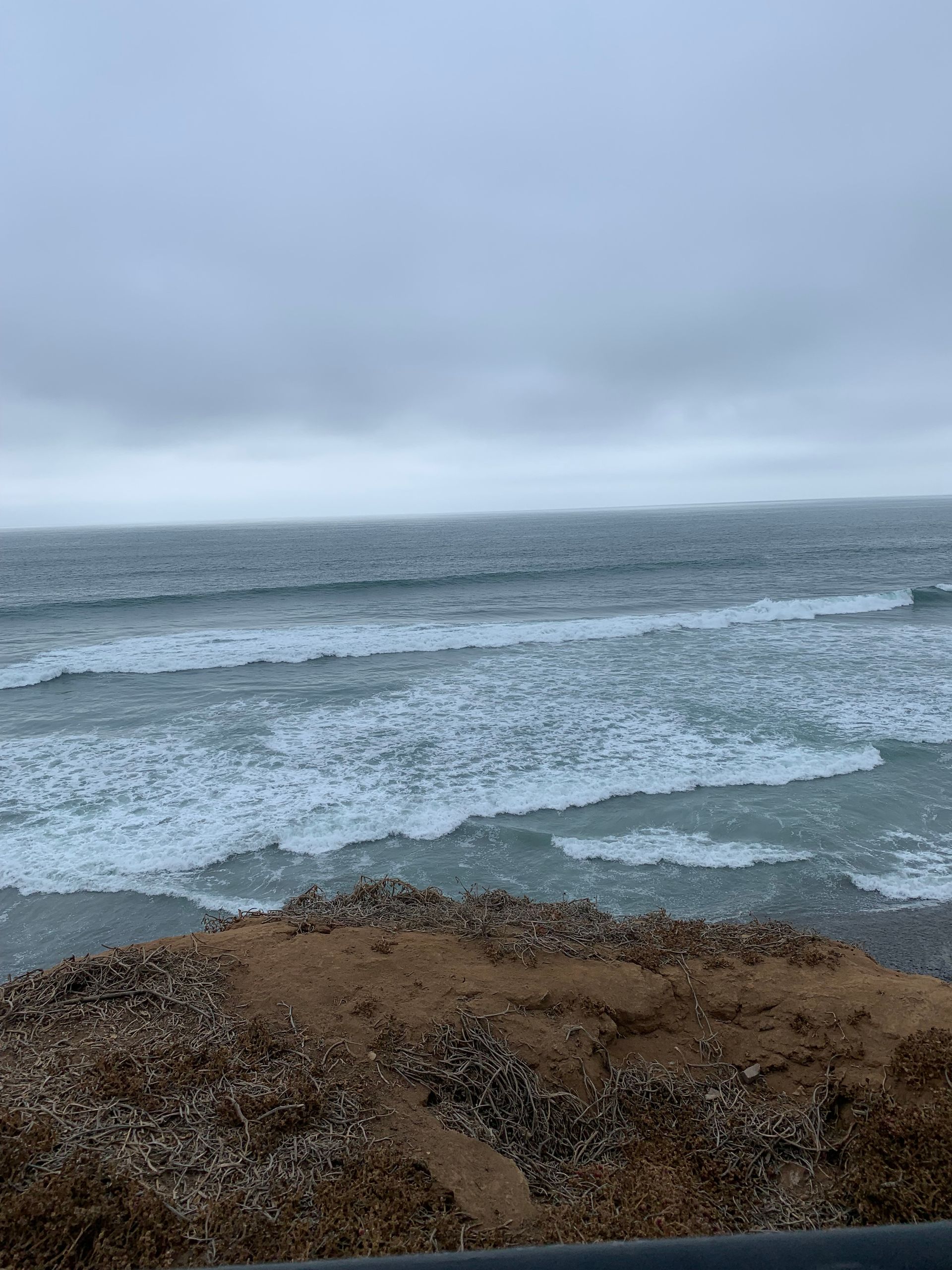 a view of the ocean from a cliff on a cloudy day .