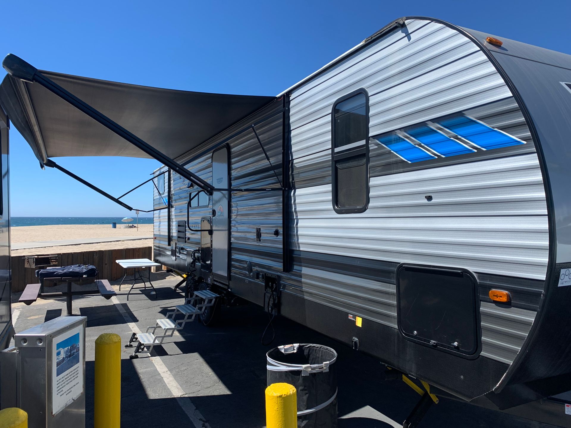 a trailer with an awning is parked next to a beach .