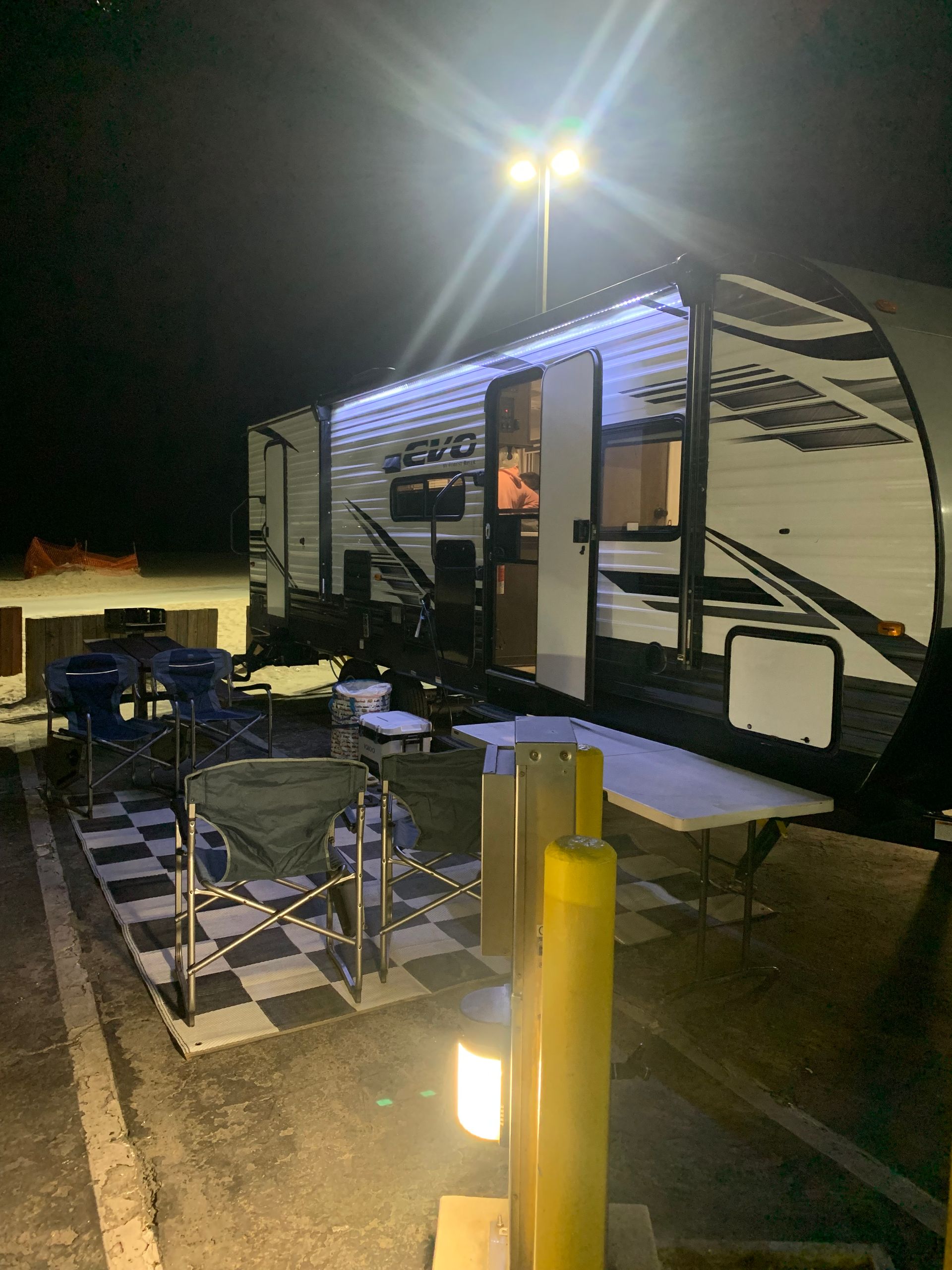 a rv is parked in a parking lot at night .