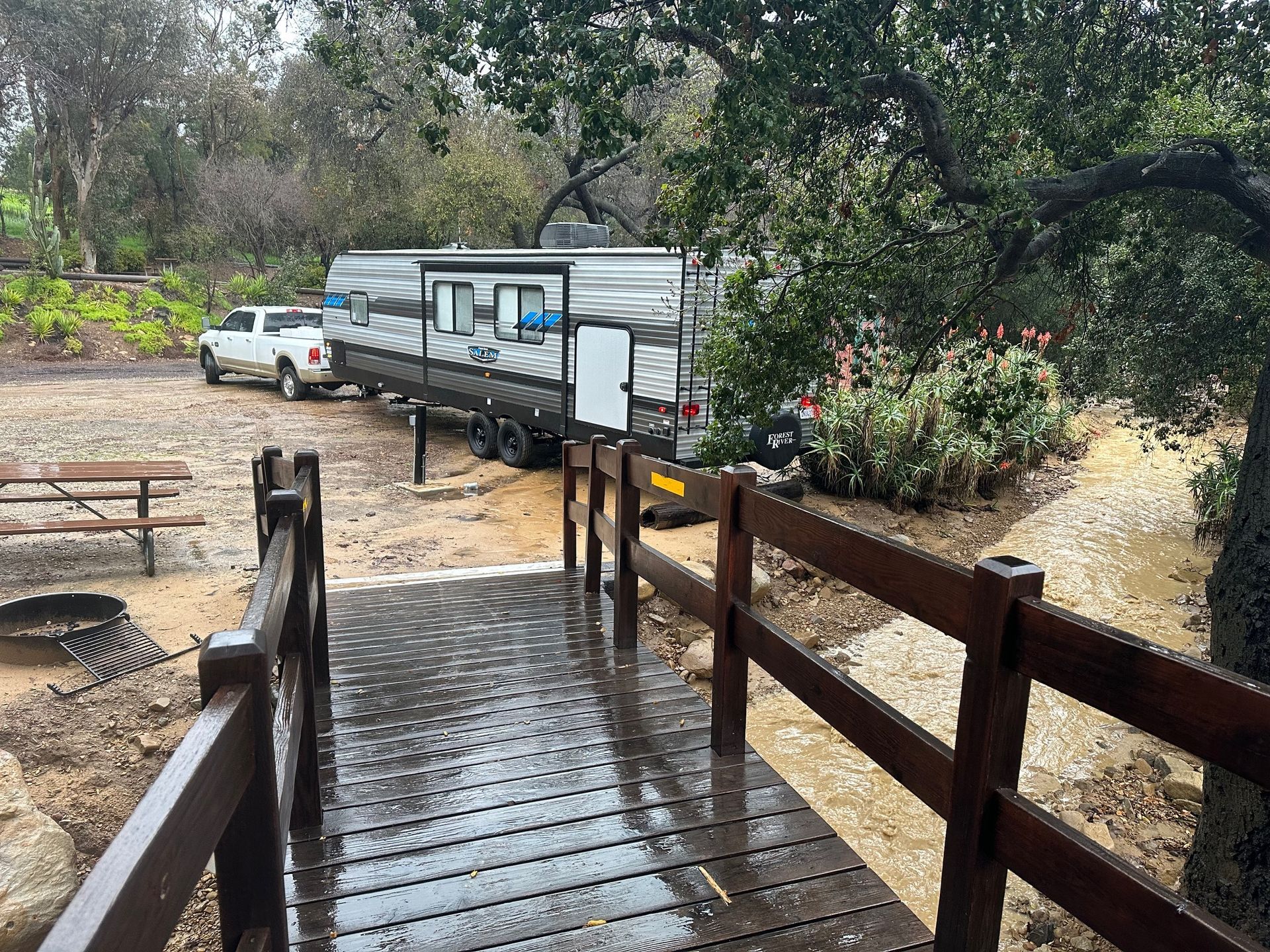 a rv is parked on the side of the road next to a wooden bridge .