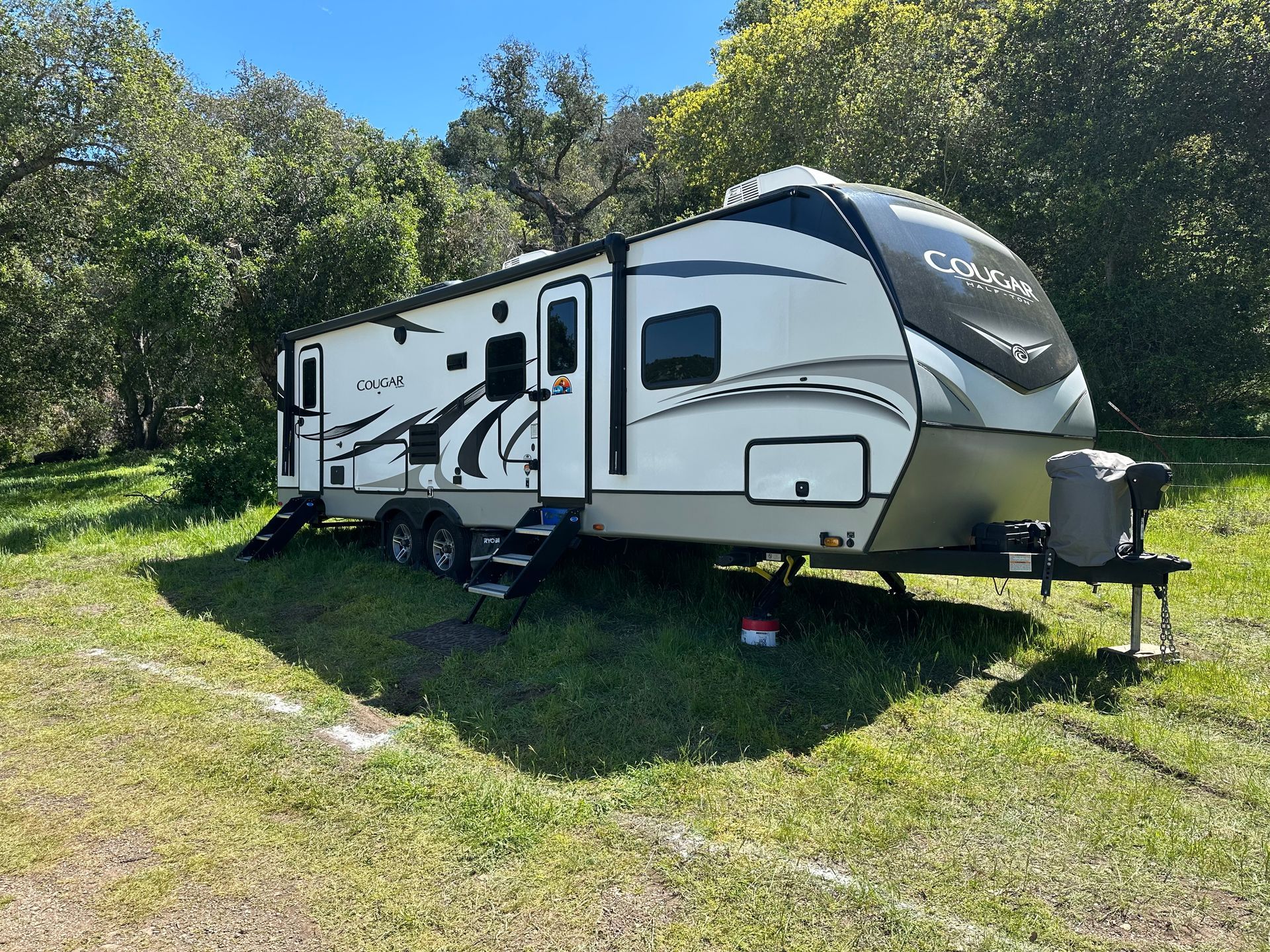 a white trailer is parked in a grassy field .