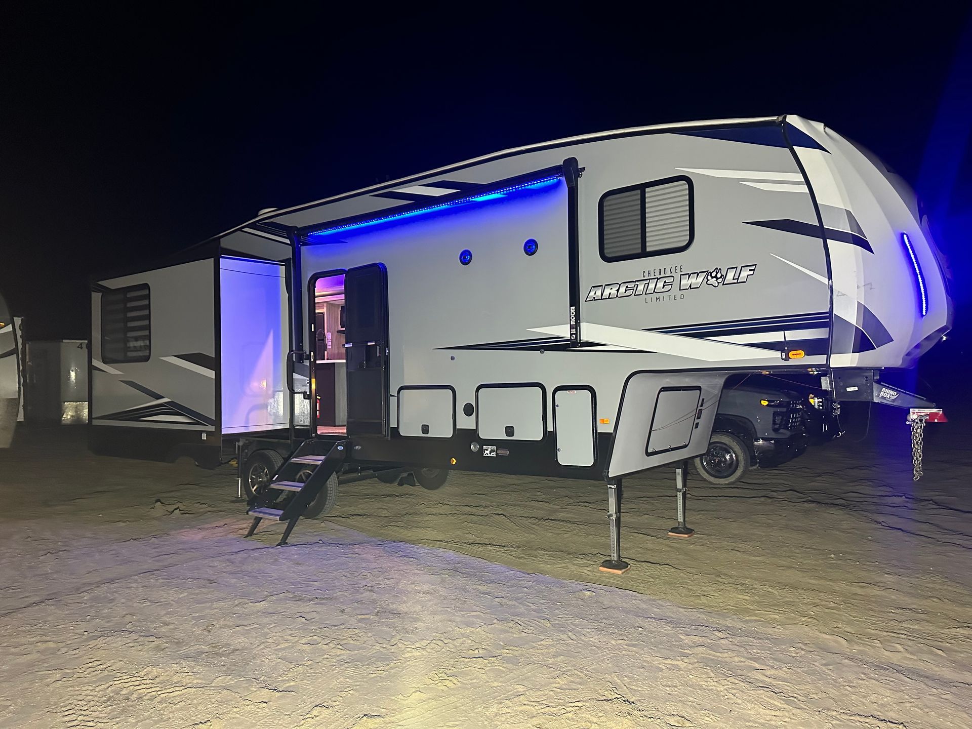 A white rv is parked in a dirt lot at night.
