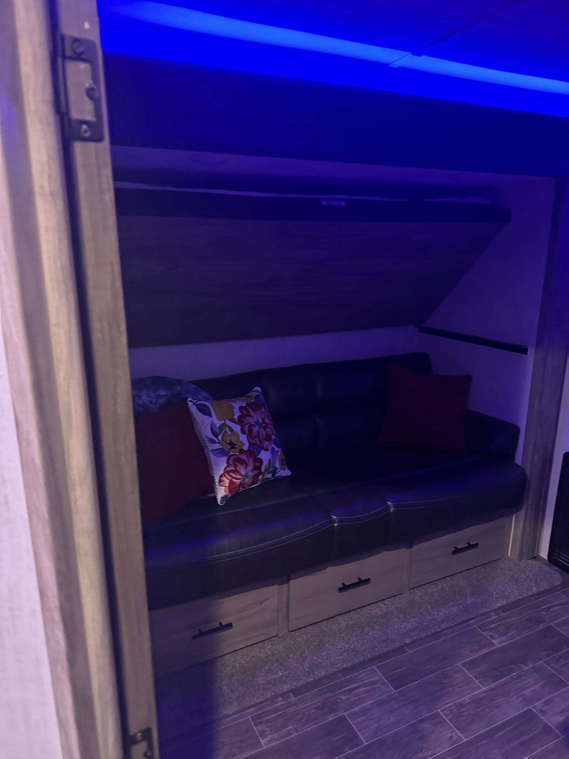 A couch is sitting under a bunk bed in a trailer.