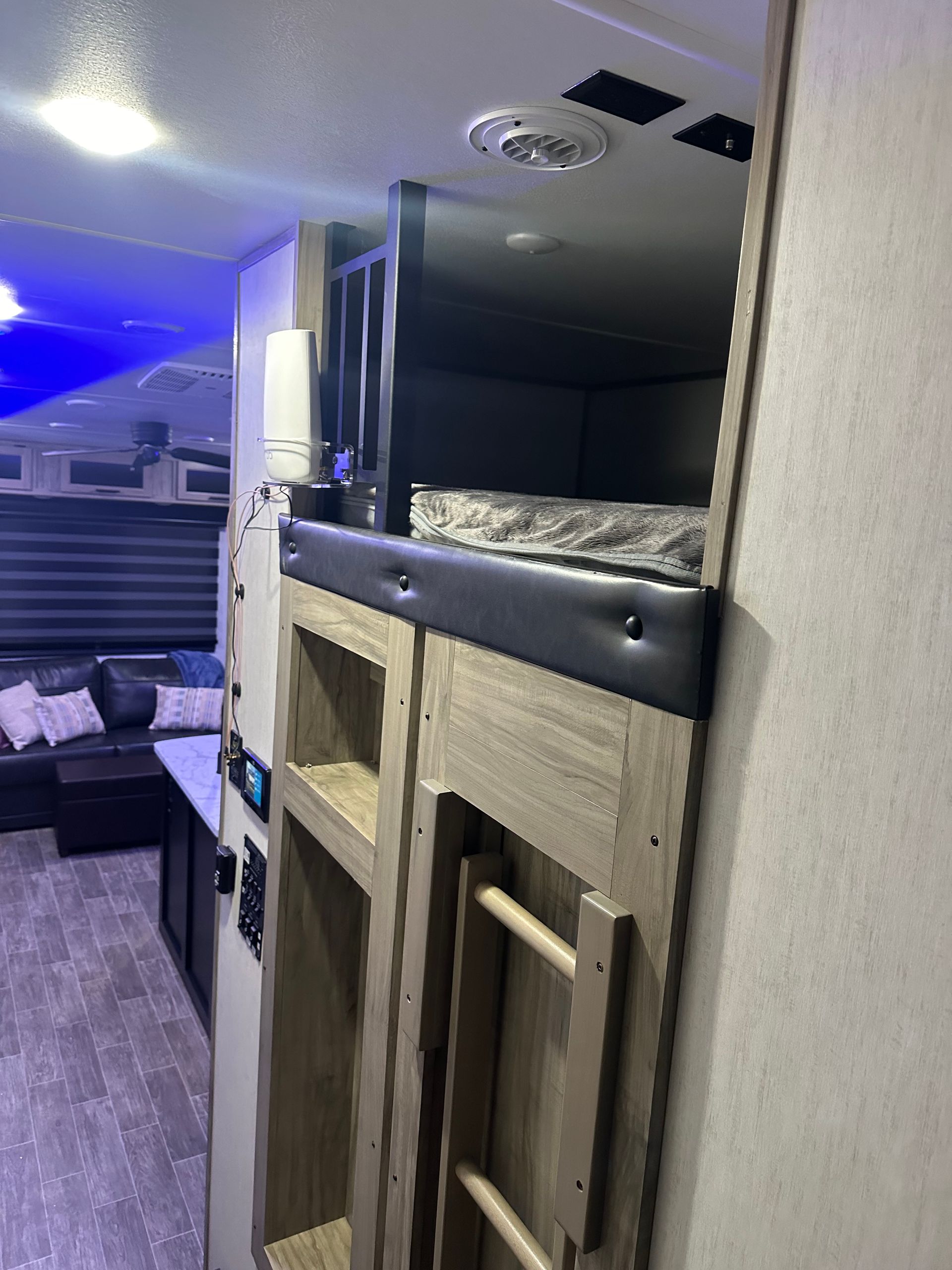 A bedroom in a rv with a bunk bed and a ladder.