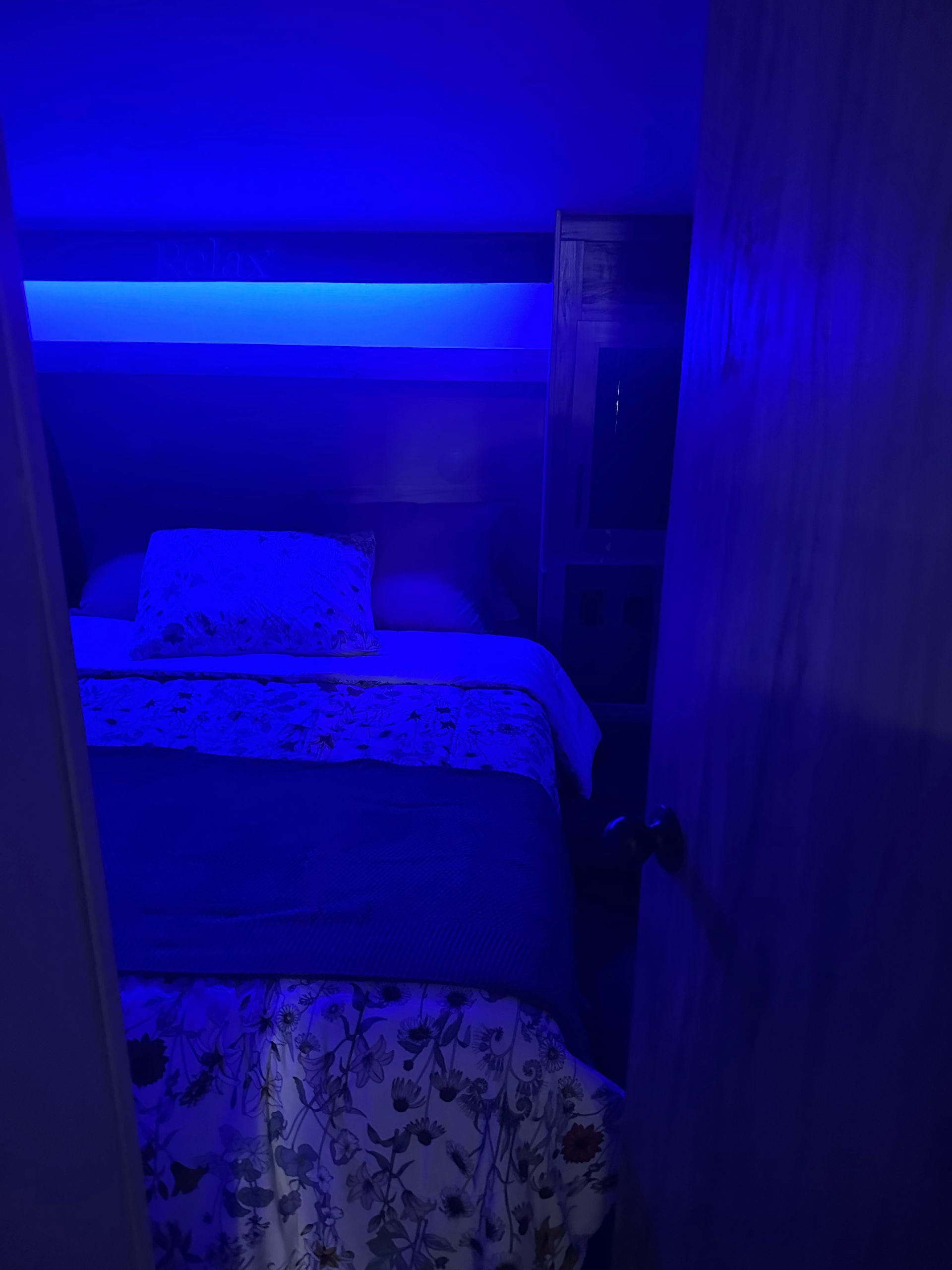 A bedroom with blue lights on the walls and a bed.