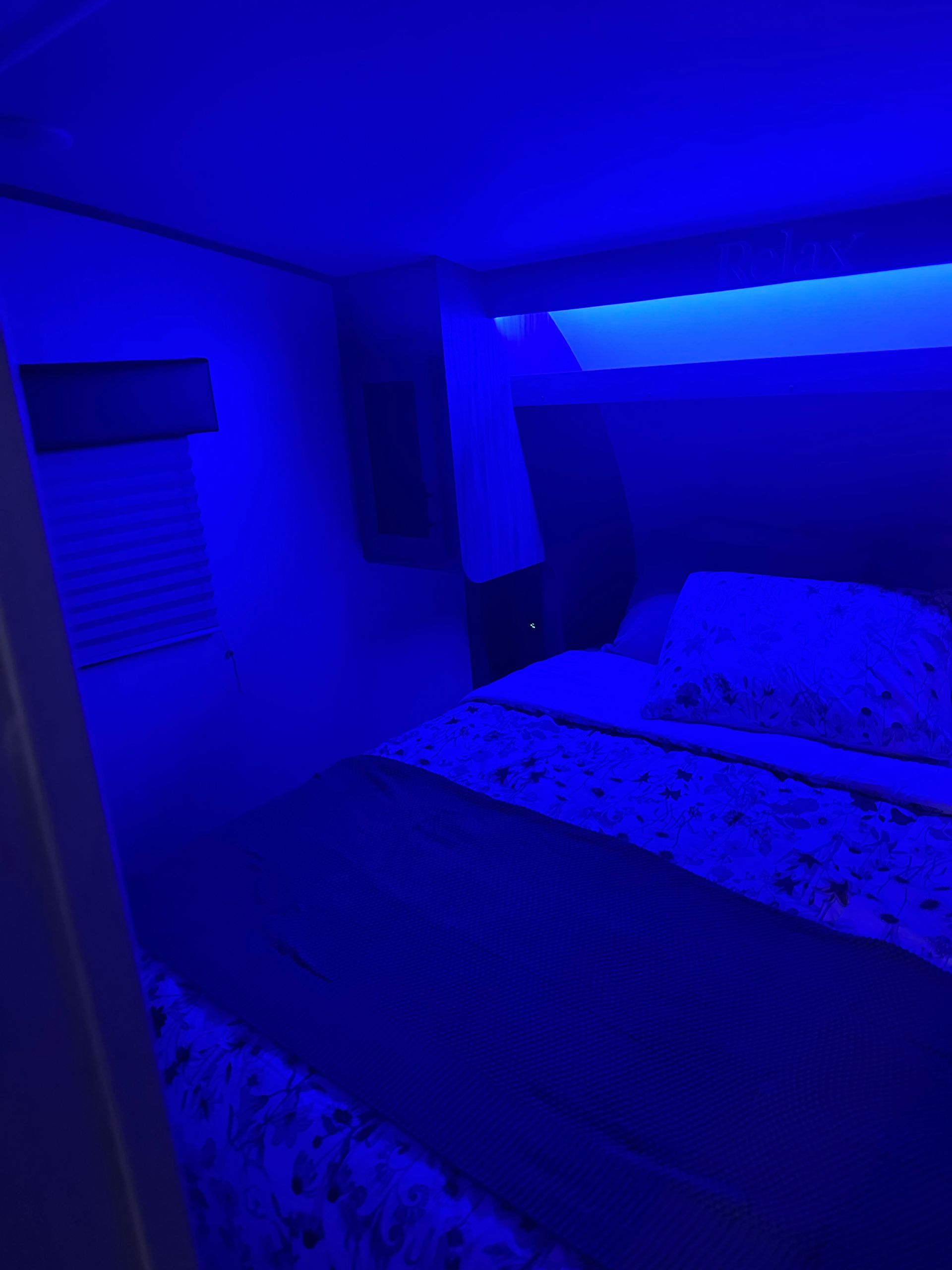 A bedroom with blue lights on the walls and a bed.