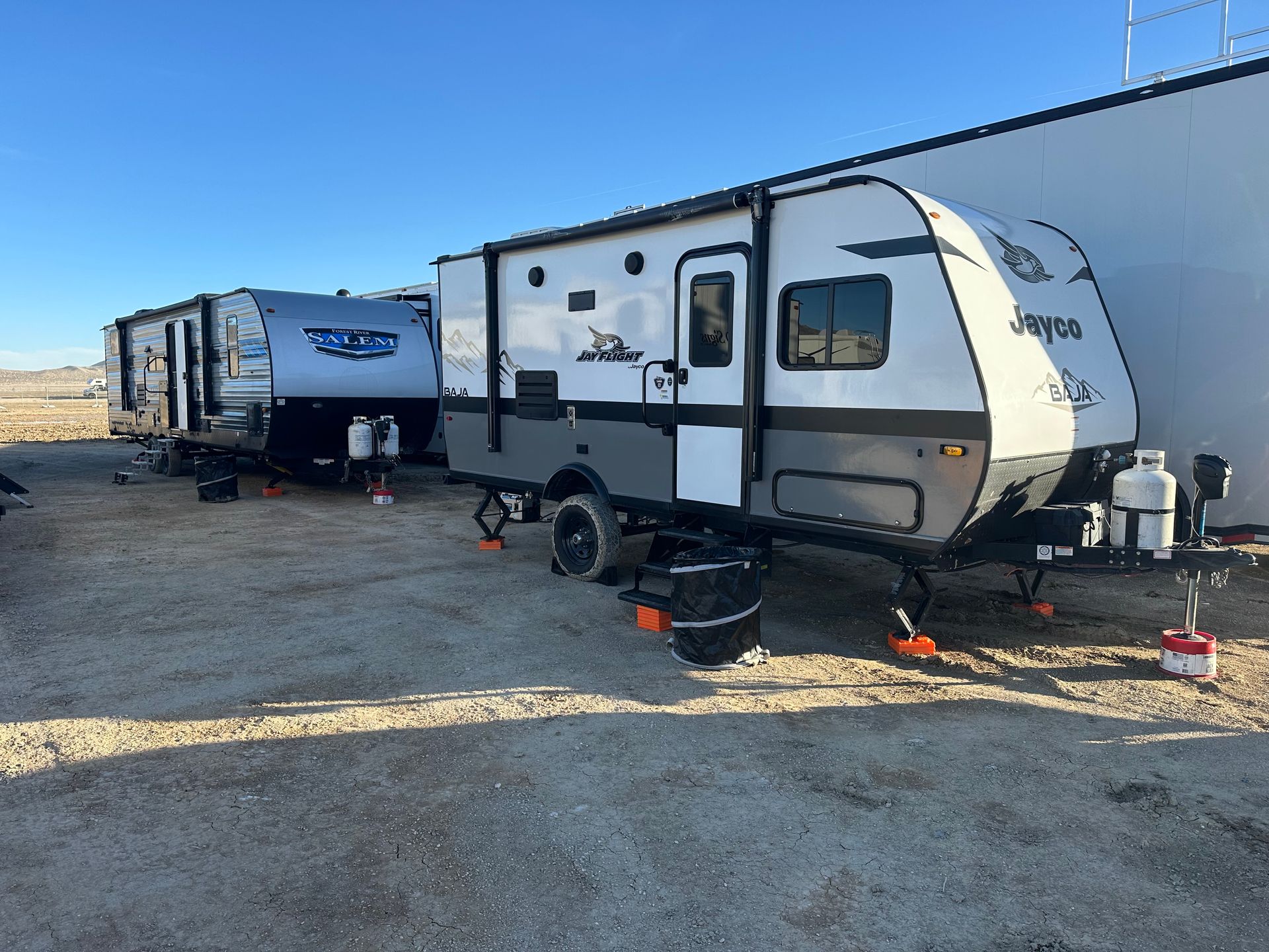 a couple of trailers are parked next to each other in a parking lot .
