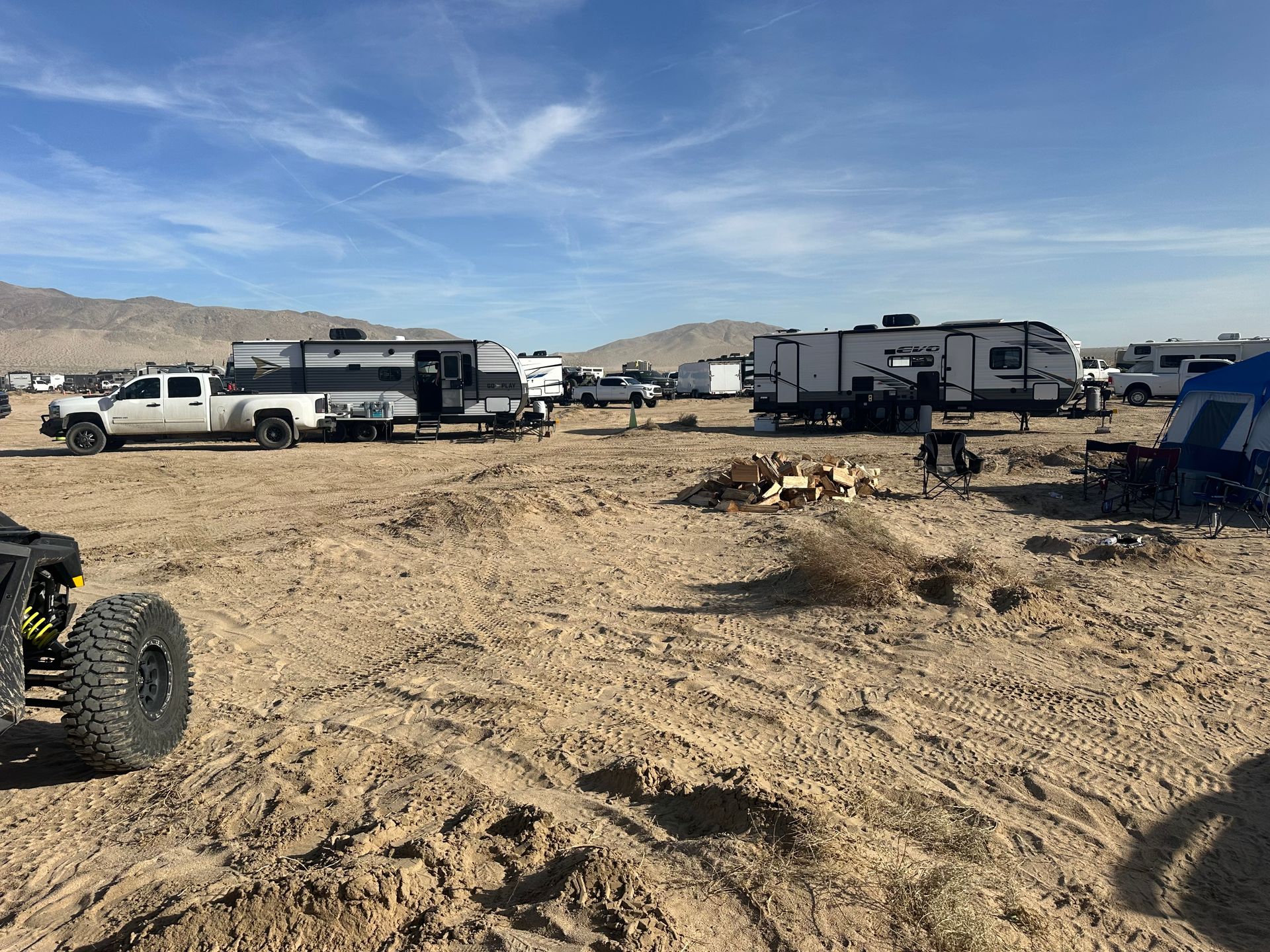 a group of trucks and trailers are parked in a dirt field .