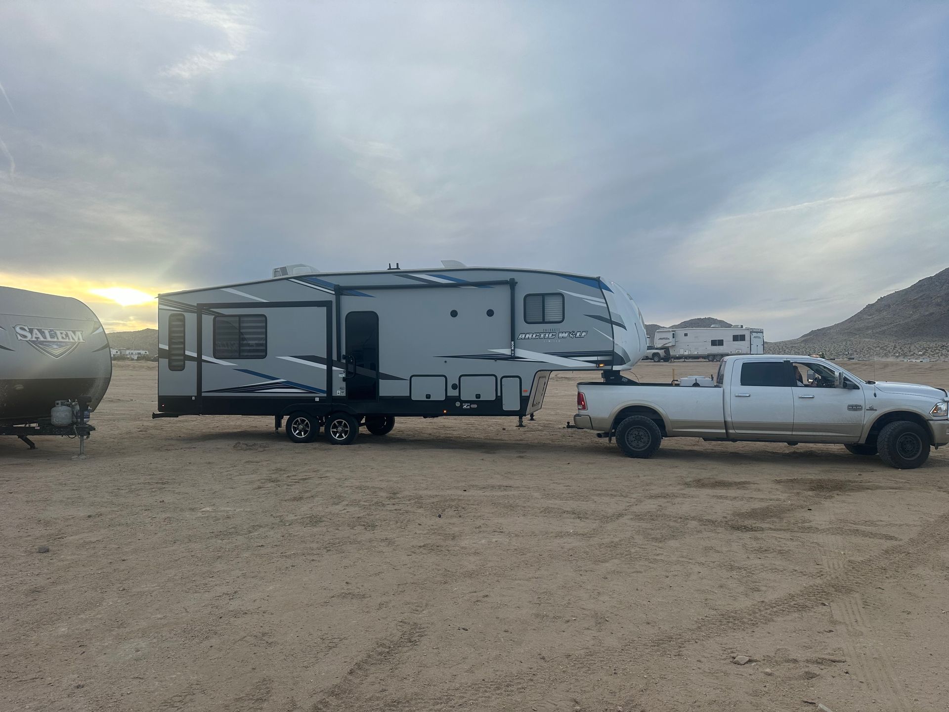 a white truck is towing a trailer in the desert .
