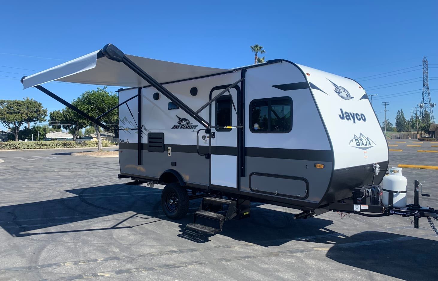 A small trailer with an awning is parked in a parking lot.