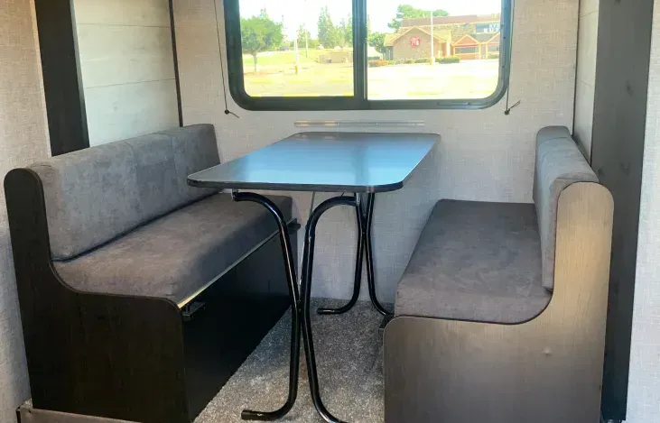 A dining area in a trailer with a table and benches.