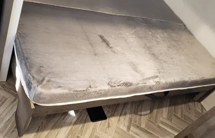 A bed is sitting on top of a wooden floor in a room.
