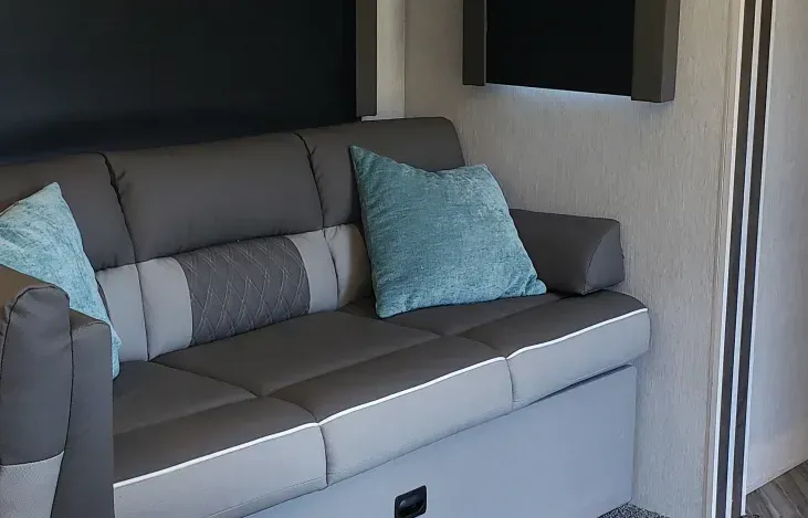 A gray and white couch with blue pillows in a living room.