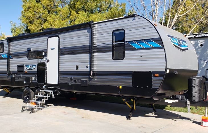 A grey and black trailer is parked in a parking lot.