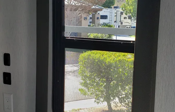A window with a view of a rv parked in the background.