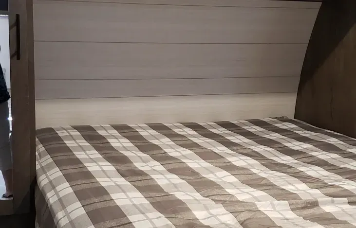 A bed with a plaid blanket on it in a room.