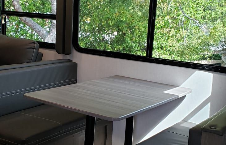 a living room in a rv with a table and couch .