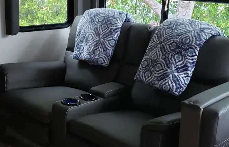 a couch and chair with blankets on them in a room with a window .