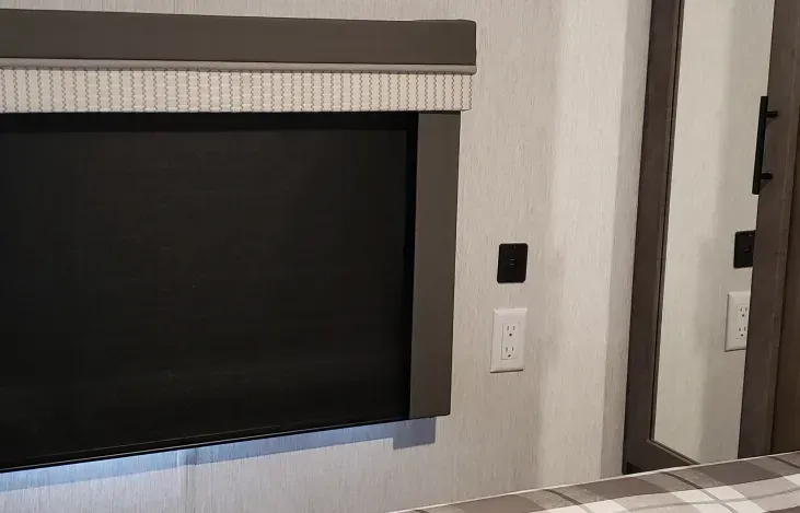 There is a television mounted on the wall next to a mirror.