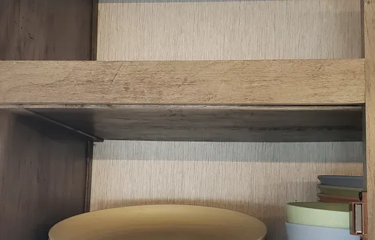 A wooden shelf with a stack of bowls on it.
