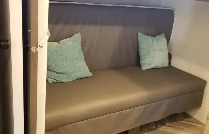 A couch with two pillows on it is sitting in a room next to a door.