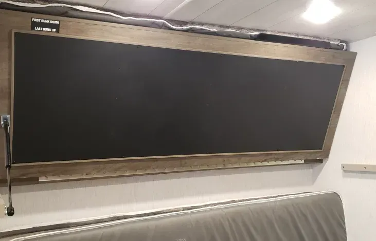 A large blackboard is hanging from the ceiling of a room.