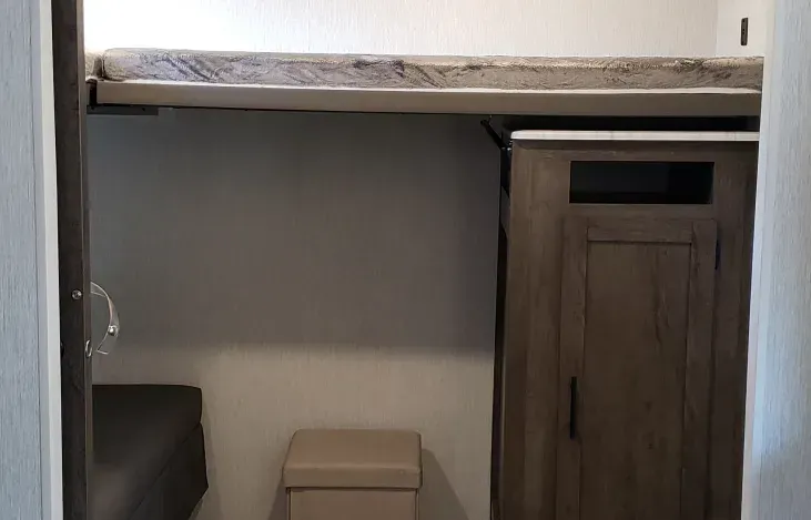 A bathroom with a toilet , cabinet , and bunk bed.