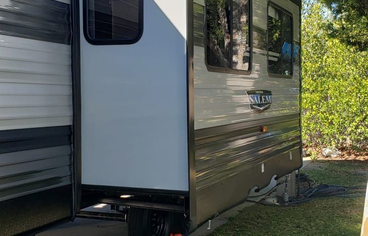 A trailer is parked in a grassy area next to a building.