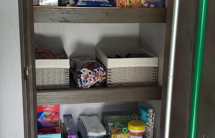 a pantry filled with lots of food and a green mop .