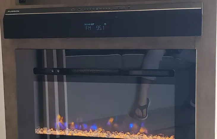A fireplace with a reflection of a person standing in front of it.