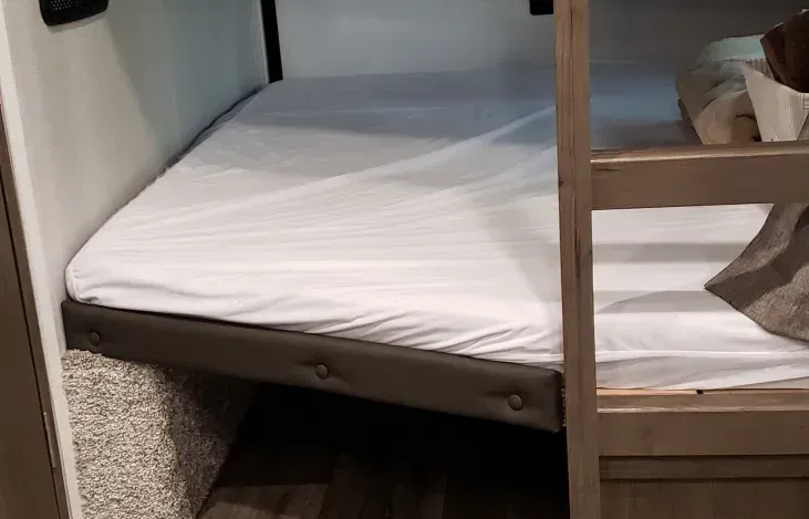 a bunk bed with a white mattress in a rv .