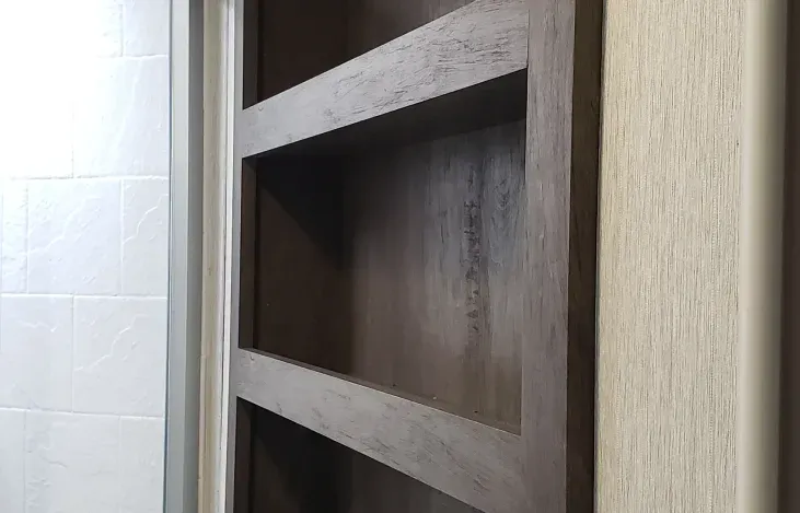 A close up of a wooden shelf in a bathroom.