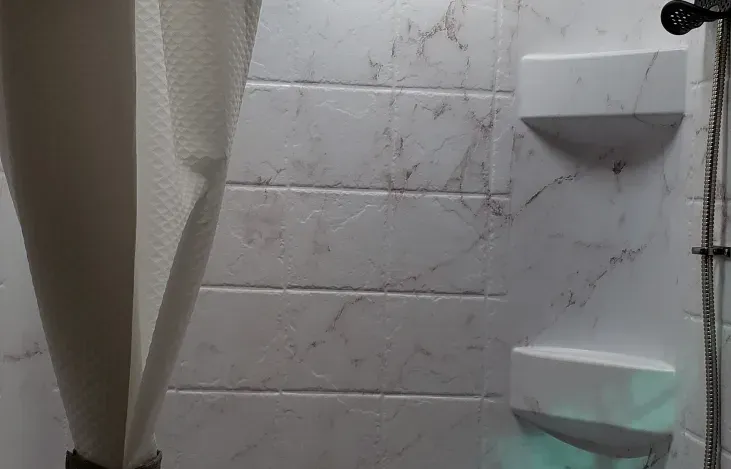 a bathroom with white tiles and a shower stall .