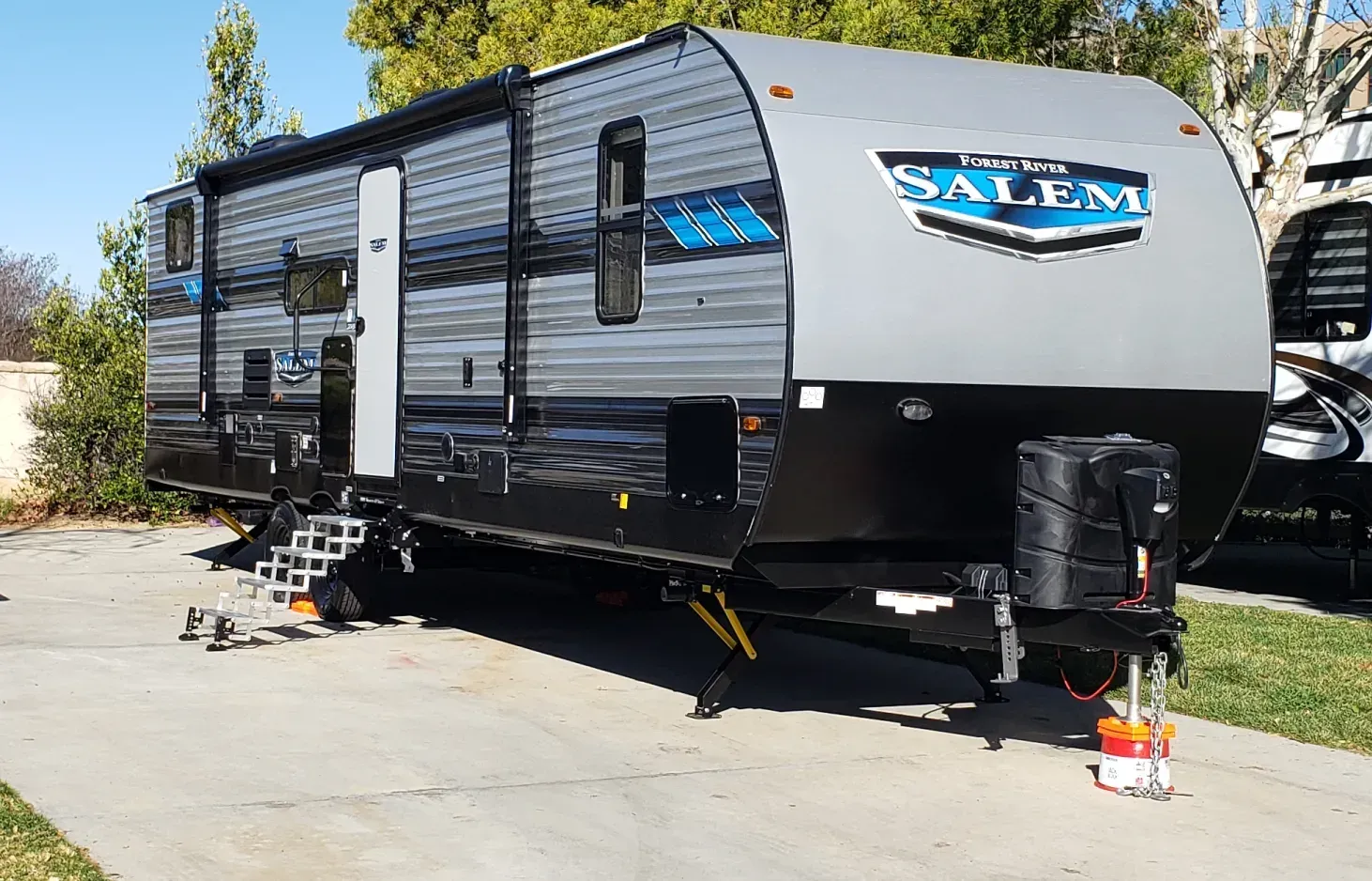 A black and gray trailer is parked in a driveway.
