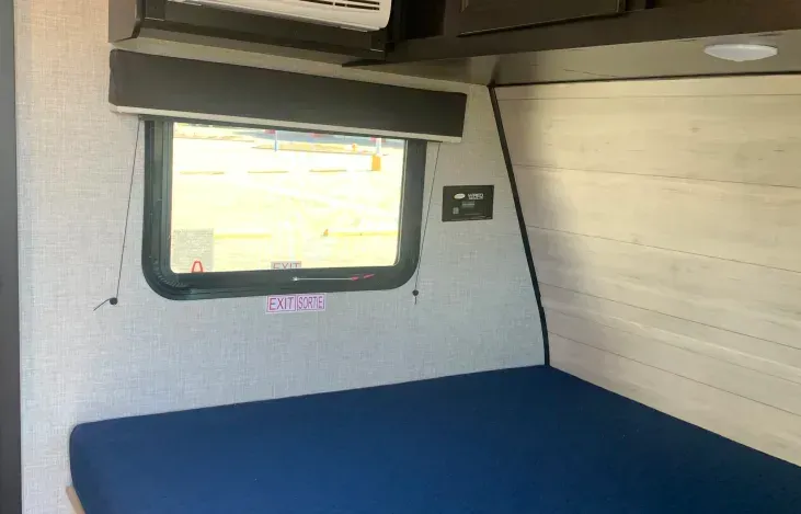 A bedroom in a camper with a bed and a window.