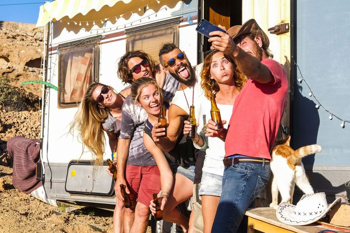 group young people friends taking selfie picture using mobile phone outside caravan trailer making funny faces holding beer bottle group young people friends taking selfie picture using mobile phone outside caravan trailer