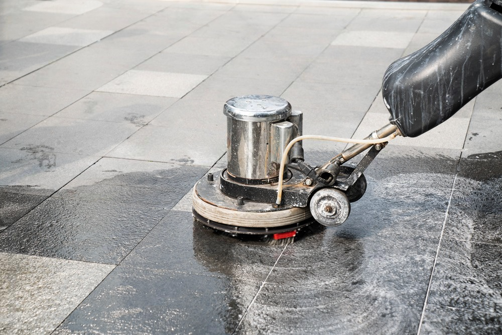 Worker using a polishing machine to clean and enhance the exterior walkway, ensuring a polished and well-maintained surface.