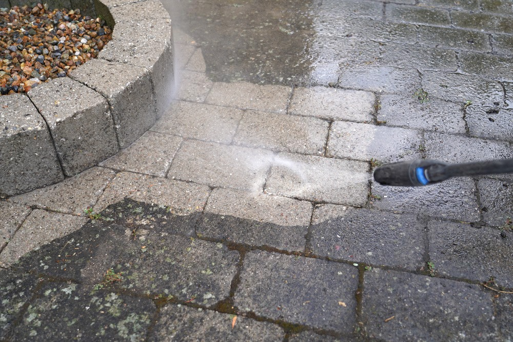 a person is cleaning a brick walkway with a high pressure washer