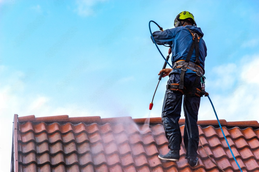 a man is spraying water on a tiled roof