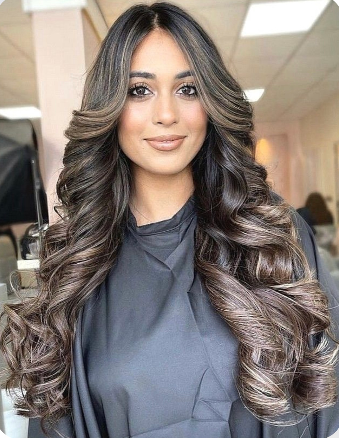 A woman with long brown hair is standing in a salon.