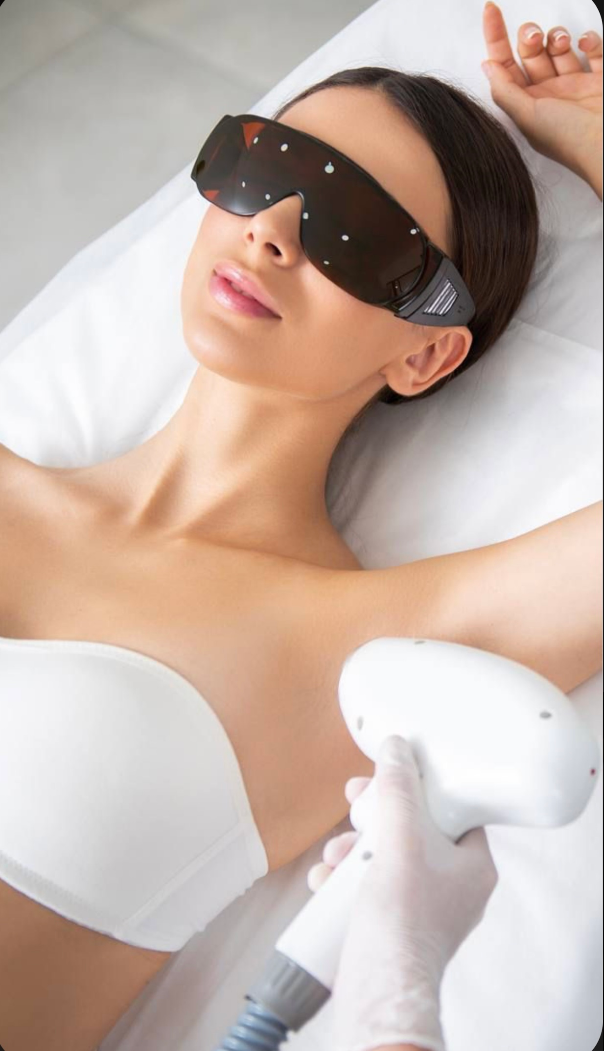 A woman is getting a laser hair removal treatment on her armpit.