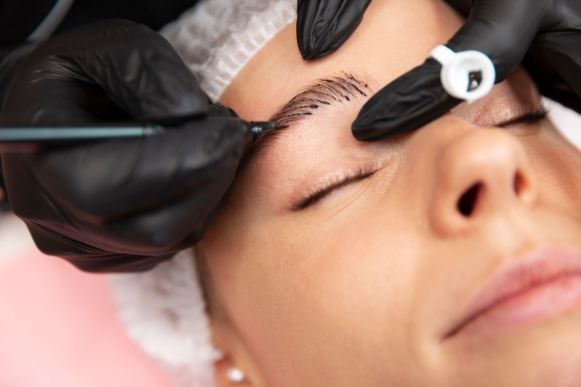 A woman is getting permanent makeup on her eyebrows.