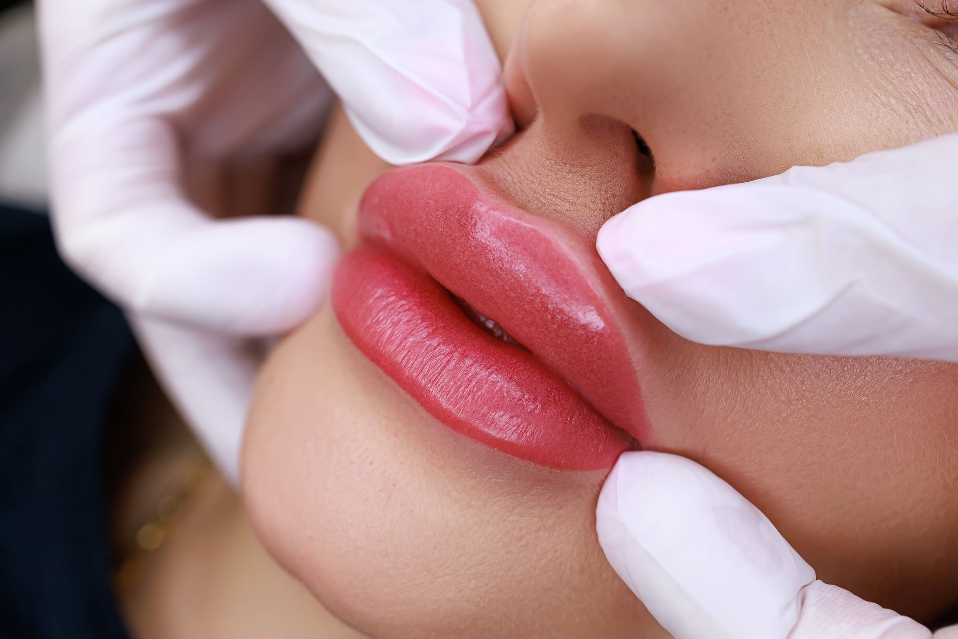 A woman is getting permanent makeup on her lips.