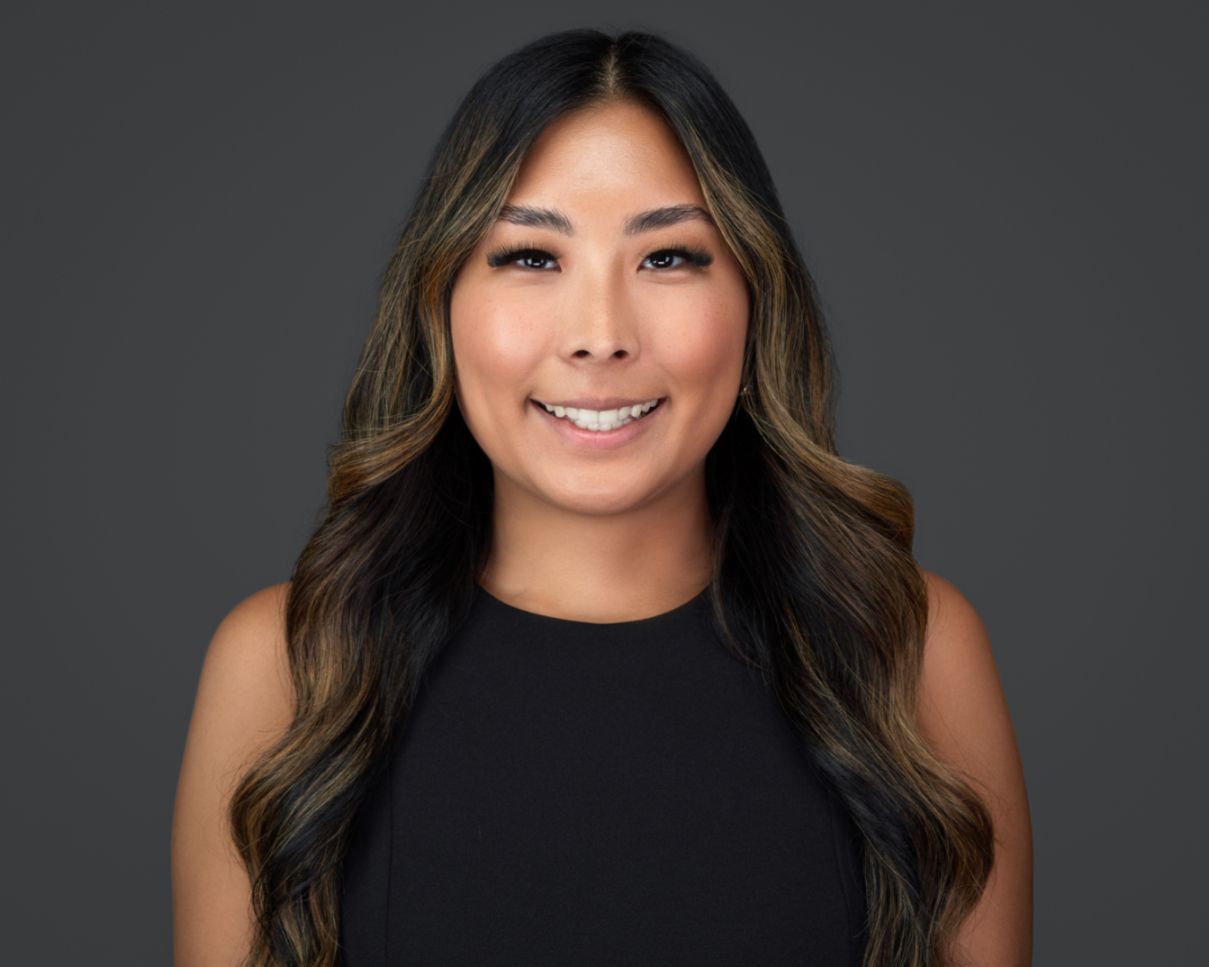 A woman with long hair is smiling and wearing a black shirt.