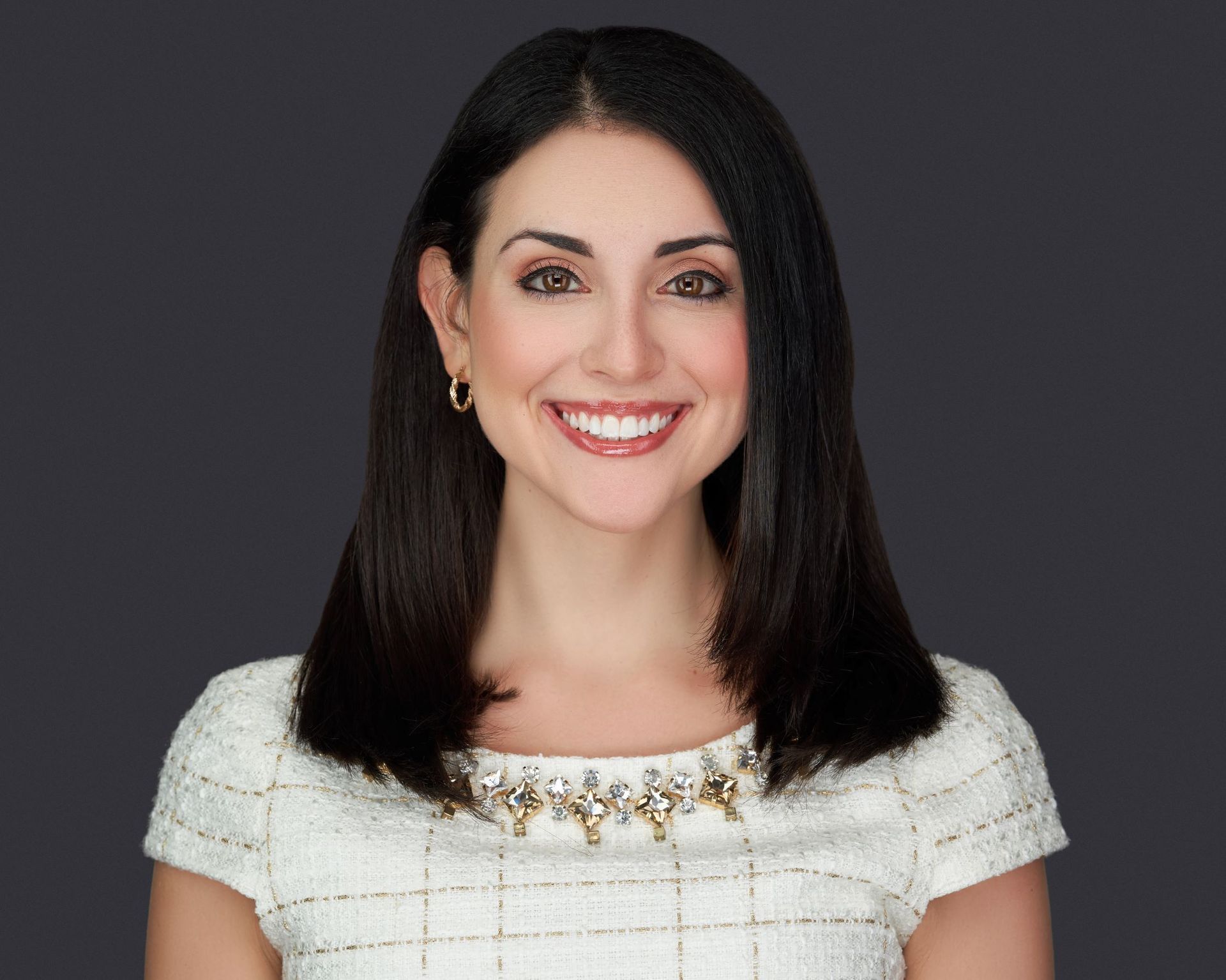 A woman in a white dress is smiling for the camera.