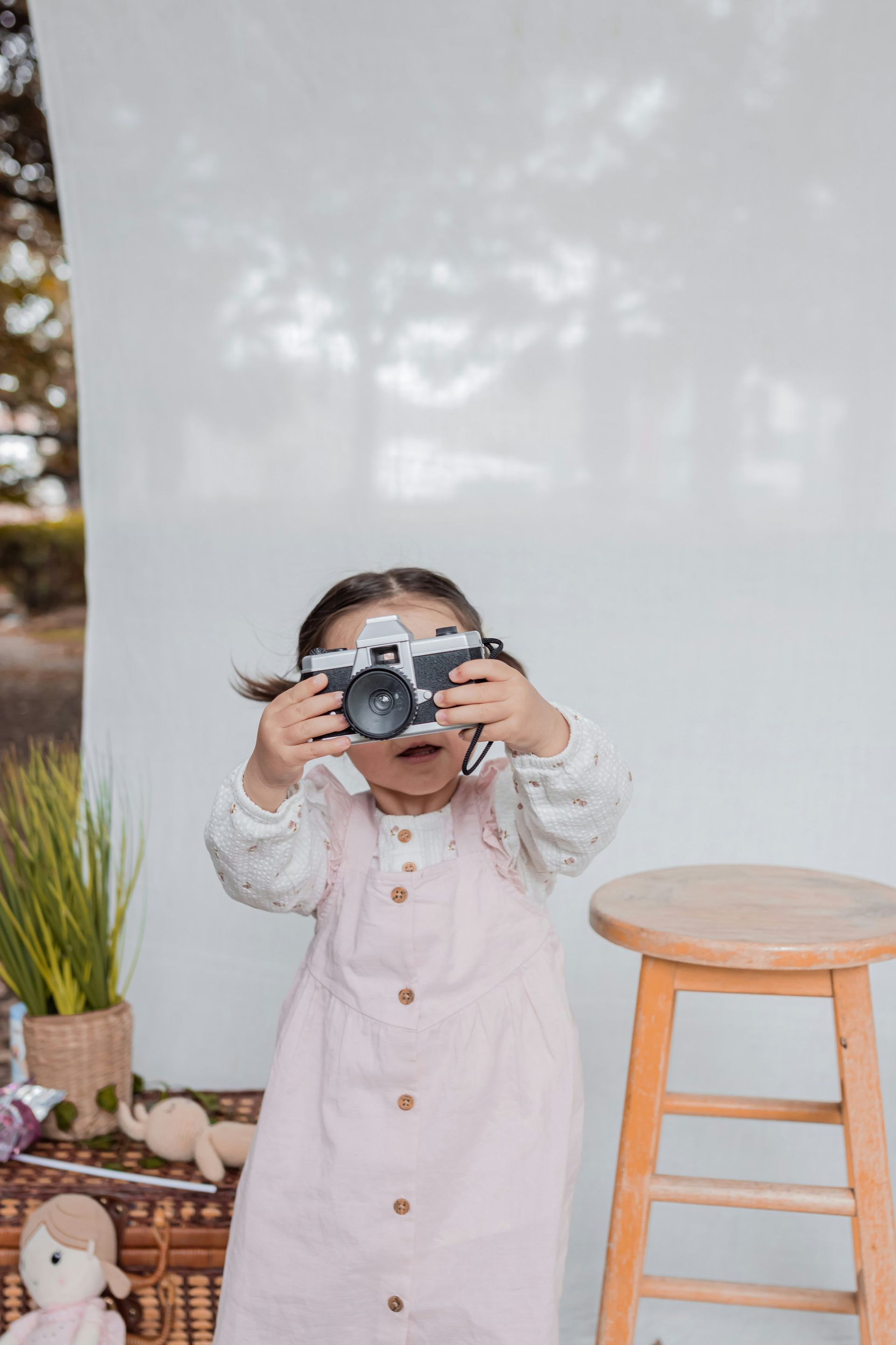 A little girl is taking a picture with a camera.