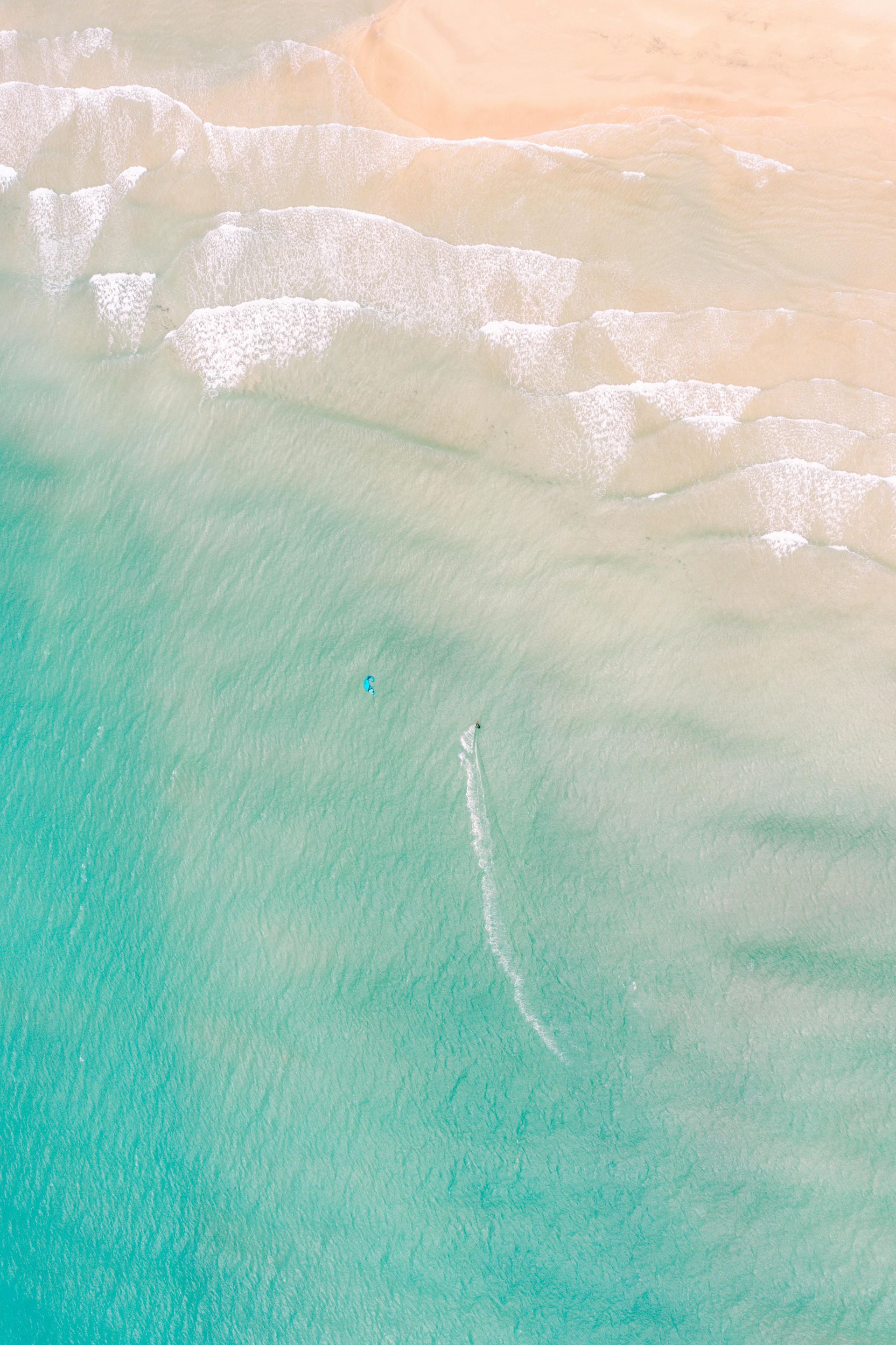 An aerial view of a beach with waves crashing on the shore.