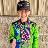 A young boy is holding a bunch of medals around his neck.